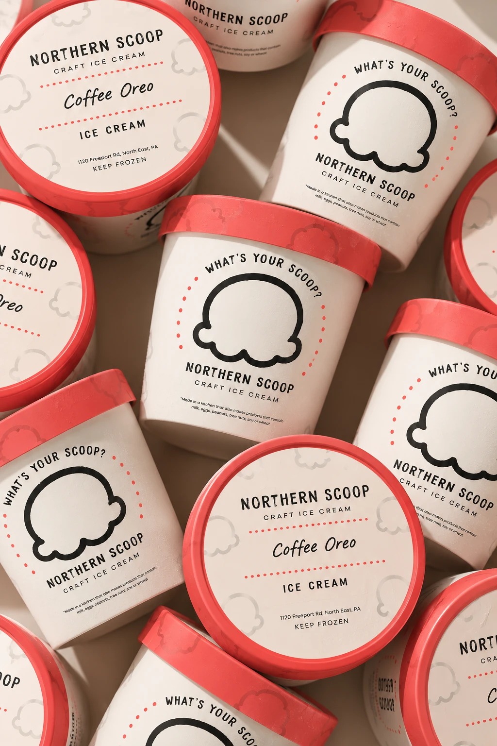 An overhead grid of Northern Scoop pint lids, one tilted off-axis